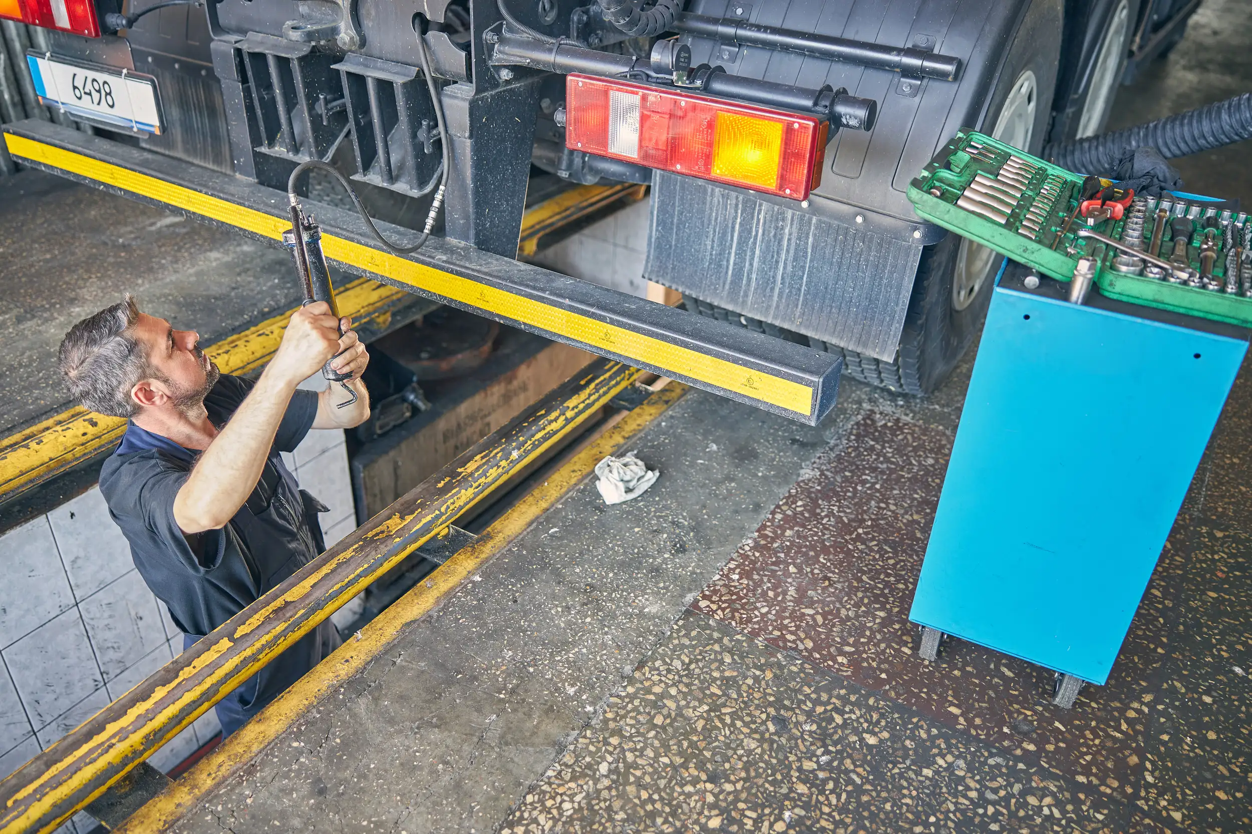 A mechanic checking and adjusting at the back of a truck