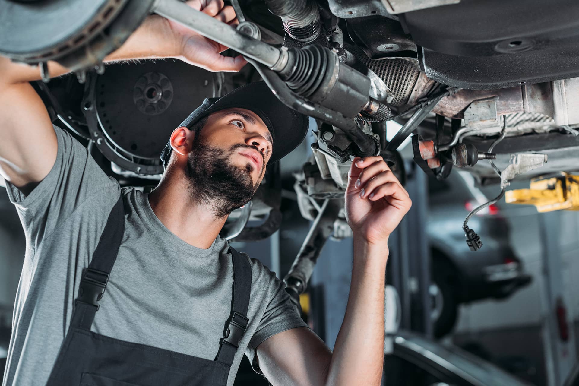 A mechanic repairing the gears and wires under the truck