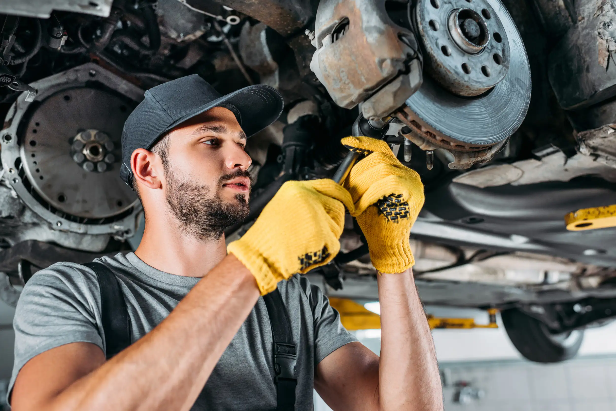 A mechanic adjusting a caliper with a tool to fix it