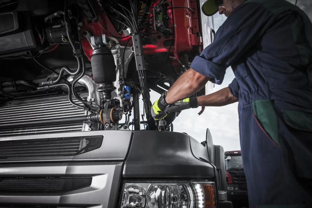 A mechanic checking and fixing the engine of the trailer truck