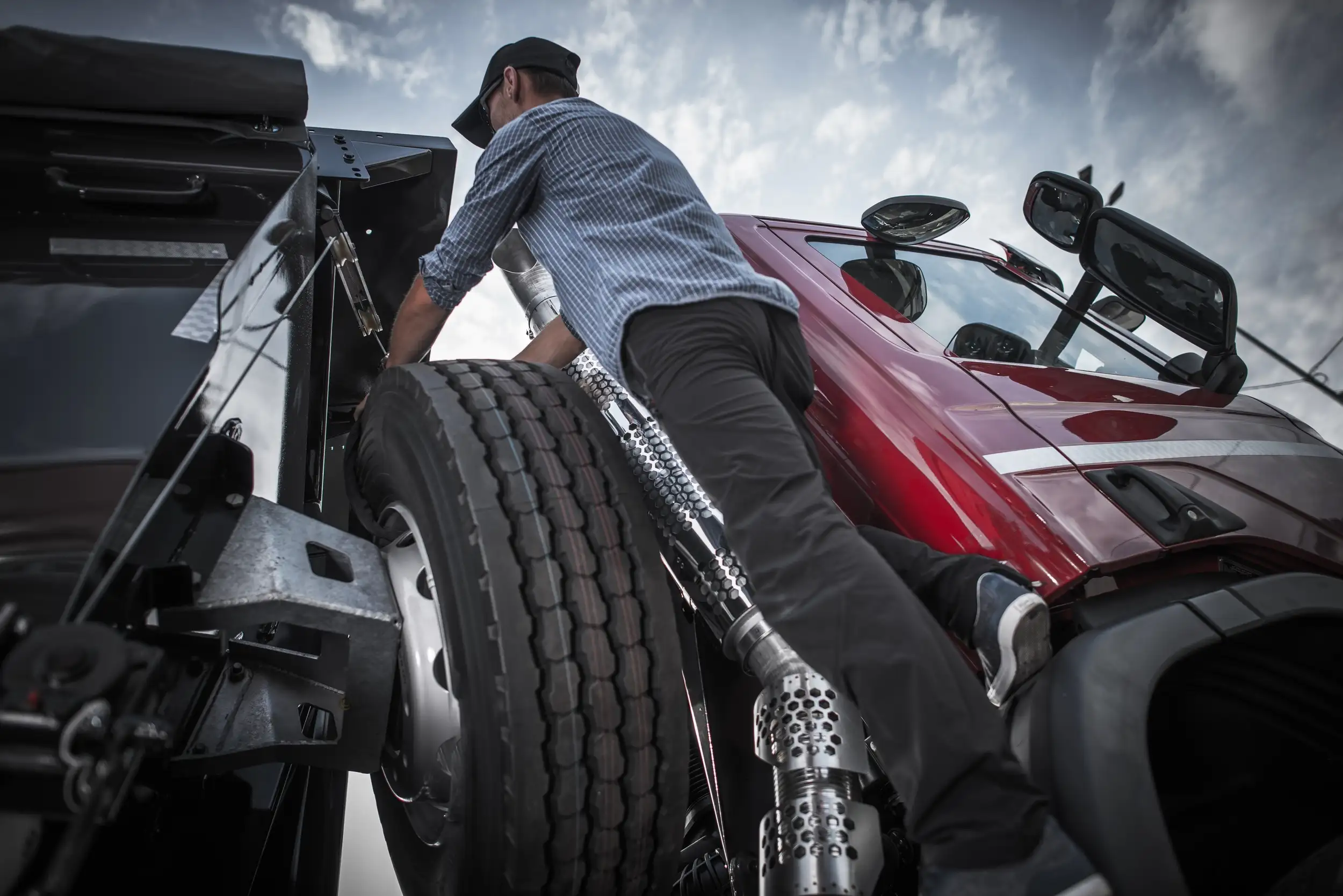 A truck driver fixing the tire of his trailer truck