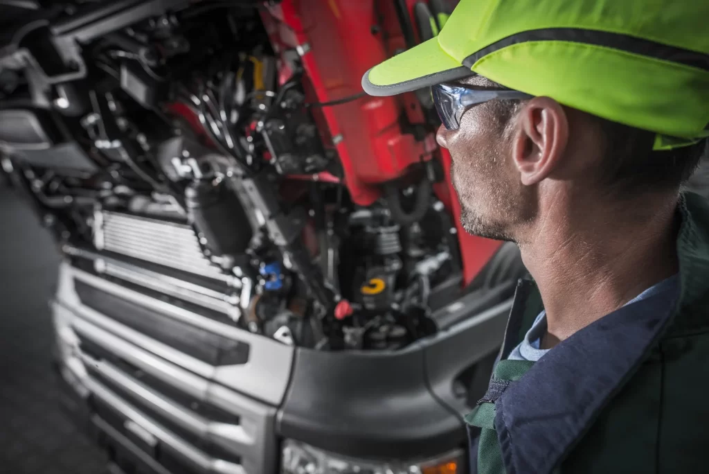 A mechanic standing next to a truck engine, ready to start a comprehensive truck repair service to ensure optimal performance