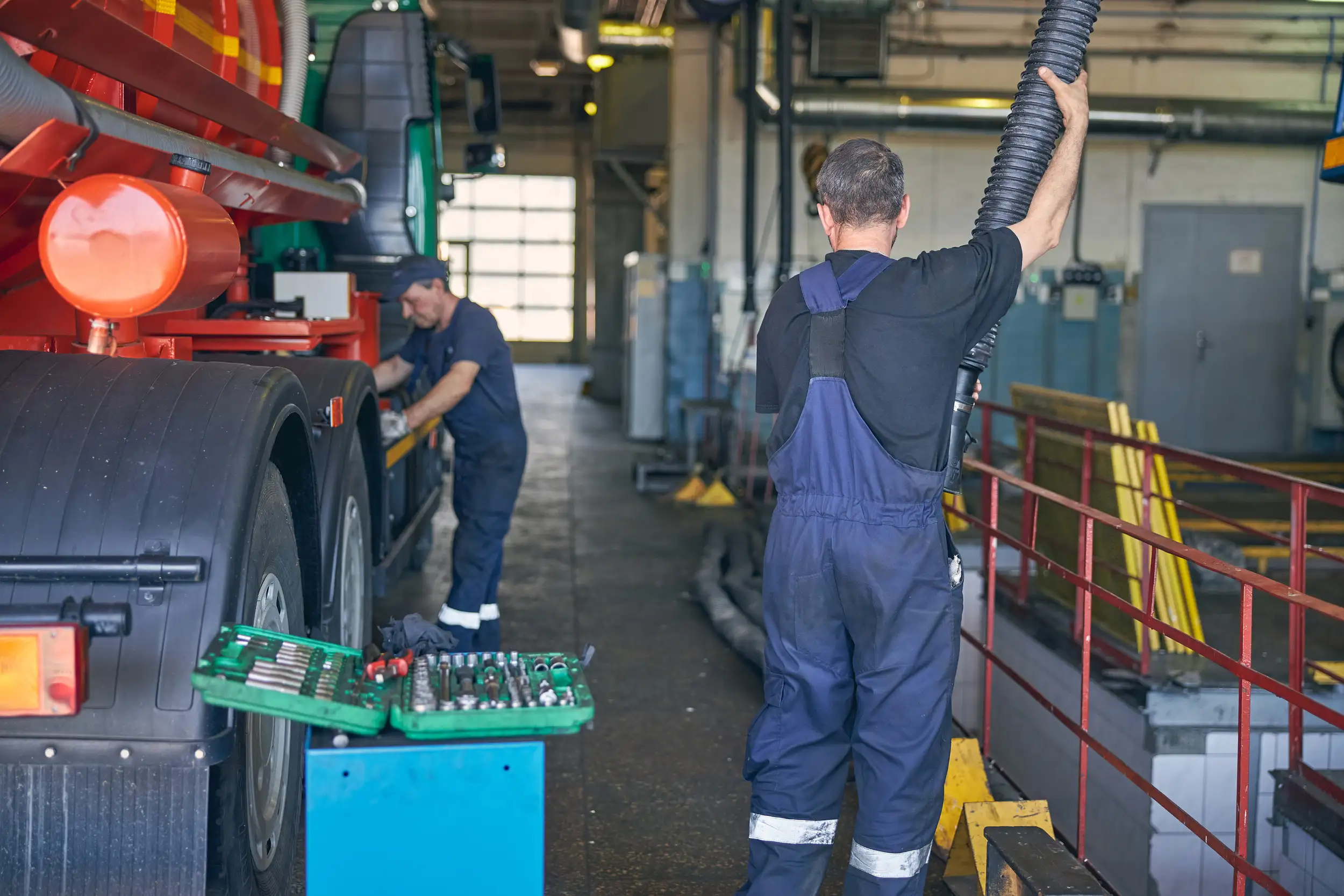 two mechanics checking the side of the trailer truck