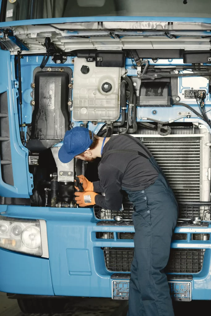 A mechanic operates on fixing the engine and wires of the trailer truck