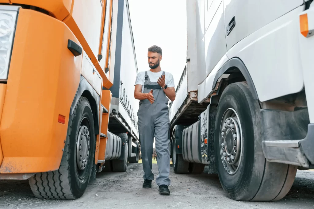 Fleet maintenance technician inspecting trucks parked side by side.