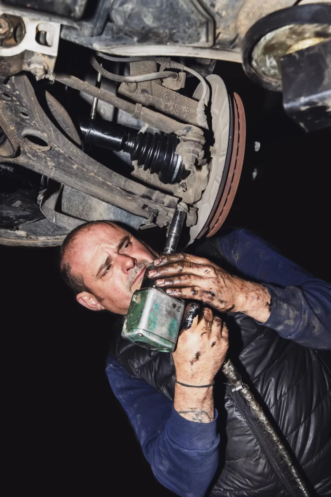 Mechanic working on a truck's suspension, highlighting the need for prompt suspension issue repairs to ensure a smooth and safe ride.