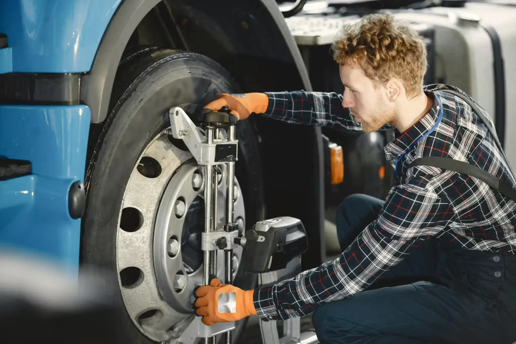 A mechanic performing truck alignment services, highlighting the importance of ensuring even tire wear.