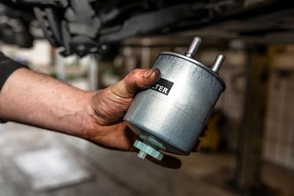 A mechanic's hand holding a new fuel filter, highlighting the need to change fuel filters for optimal vehicle performance.