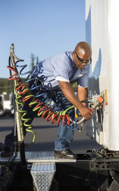 A mechanic black man adjusting the exhaust of a trailer truck