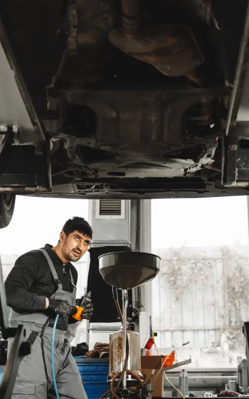 A mechanic checking and changing oil under the truck